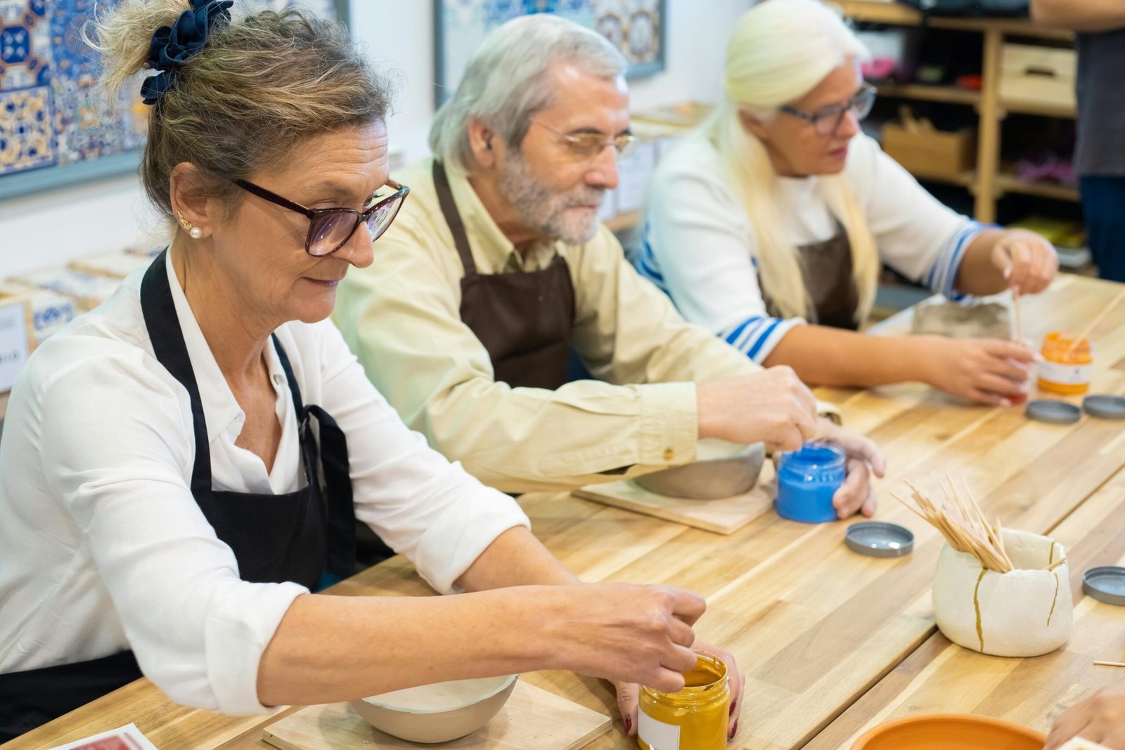 VOLUNTARIADO Senior adults enjoying a pottery painting workshop, showcasing creativity and craftsmanship.